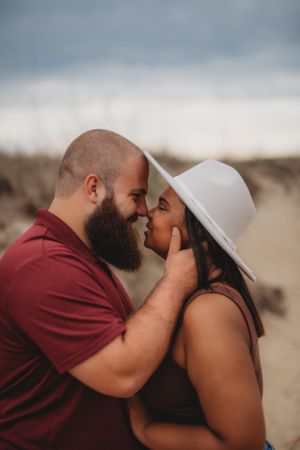 A romantic close-up portrait of a couple sharing a tender moment on the beach.