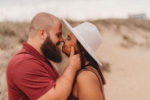 An intimate moment captured between a couple against soft sand dunes.