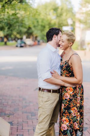 Two people share an intimate moment outdoors on a brick pathway in summer.