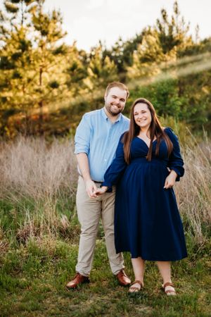 Couple poses together on hillside during golden hour.