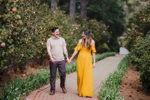 Couple strolling hand in hand on brick path through garden.