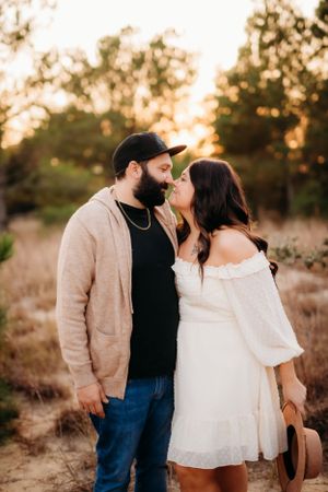 Romantic couple sharing intimate moment during sunset photo session in field.