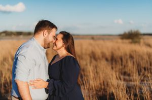 Intimate couple sharing tender moment in golden wheat field at sunset.