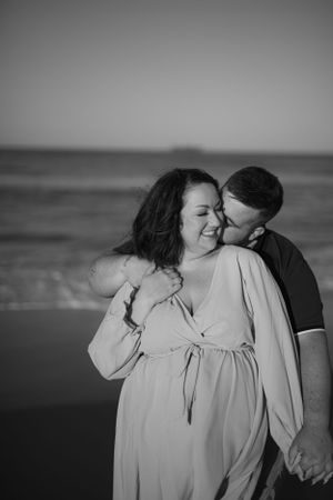 Romantic black and white beach portrait of a couple sharing an intimate moment.