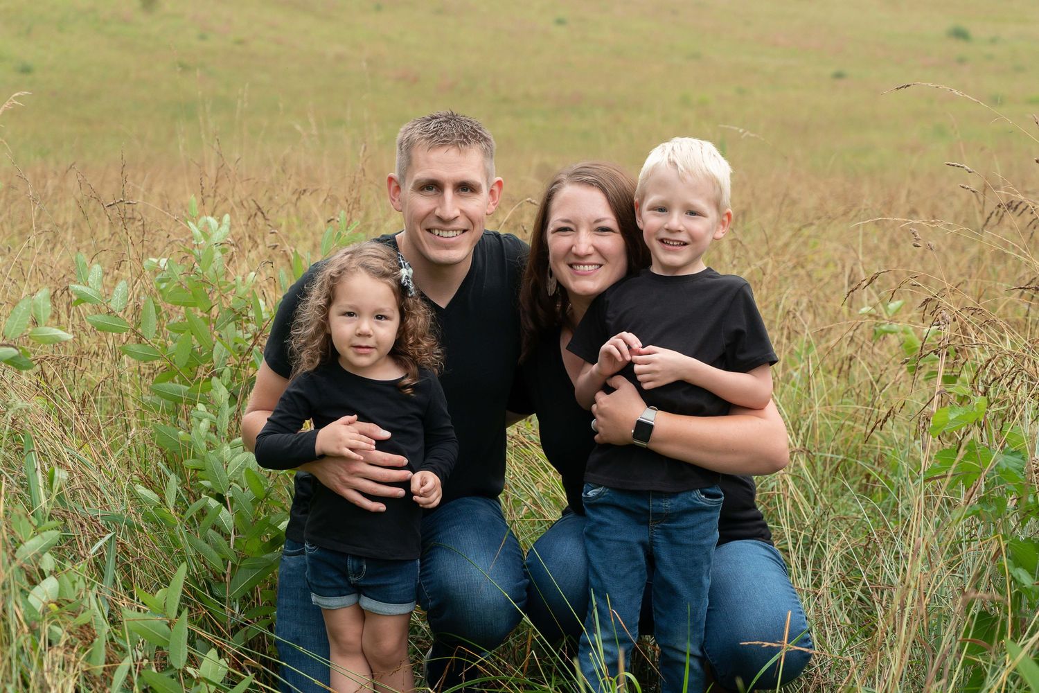 family grins surrounded by fields of grass