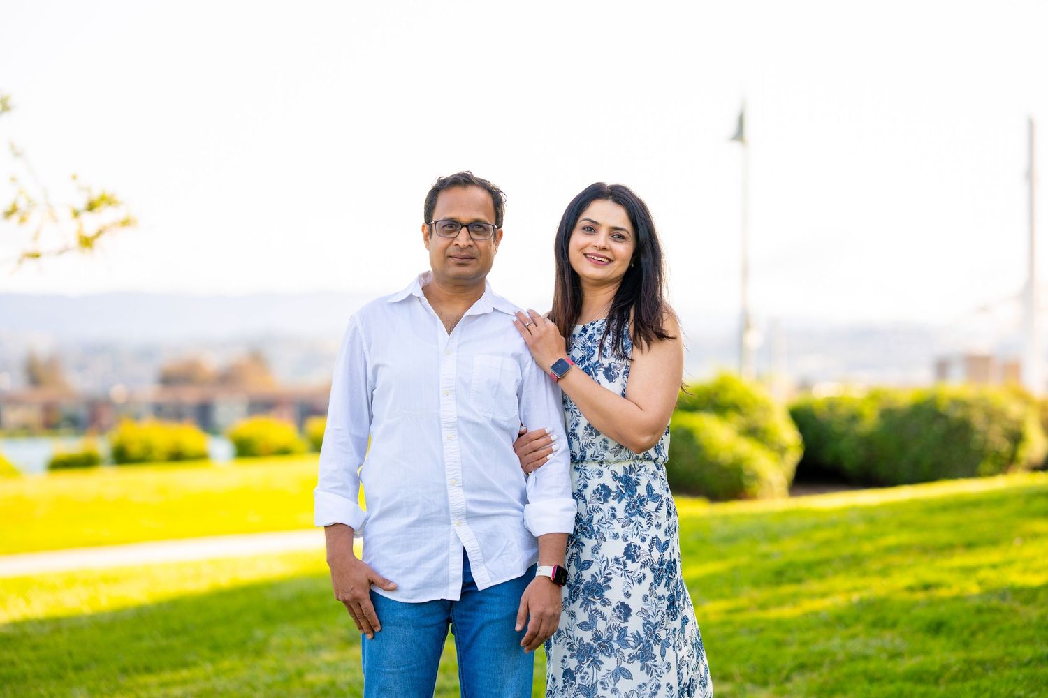 Couple stands together on hilltop with scenic background during outdoor photoshoot.