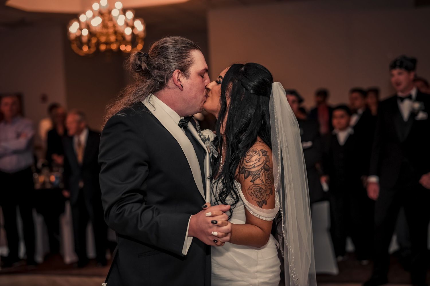 Wedding reception dance captured in warm ambient lighting with guests in background.