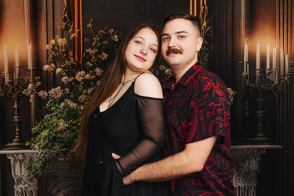 Romantic couple portrait with candlelit backdrop and floral decorations.
