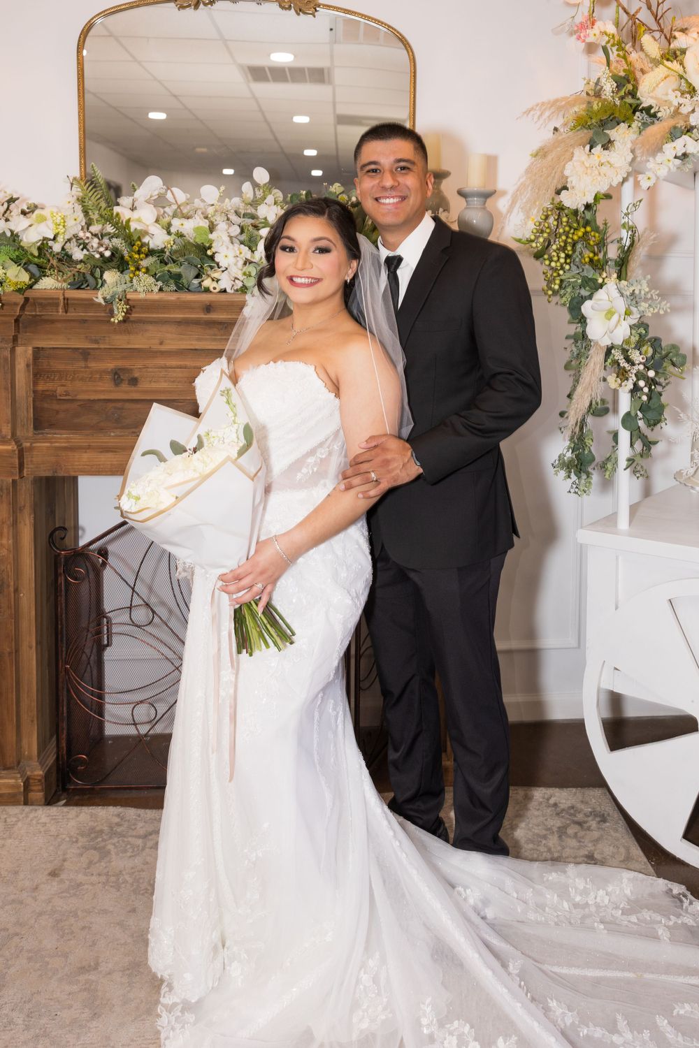 Elegant wedding portrait with floral arch and wooden decor in indoor venue.