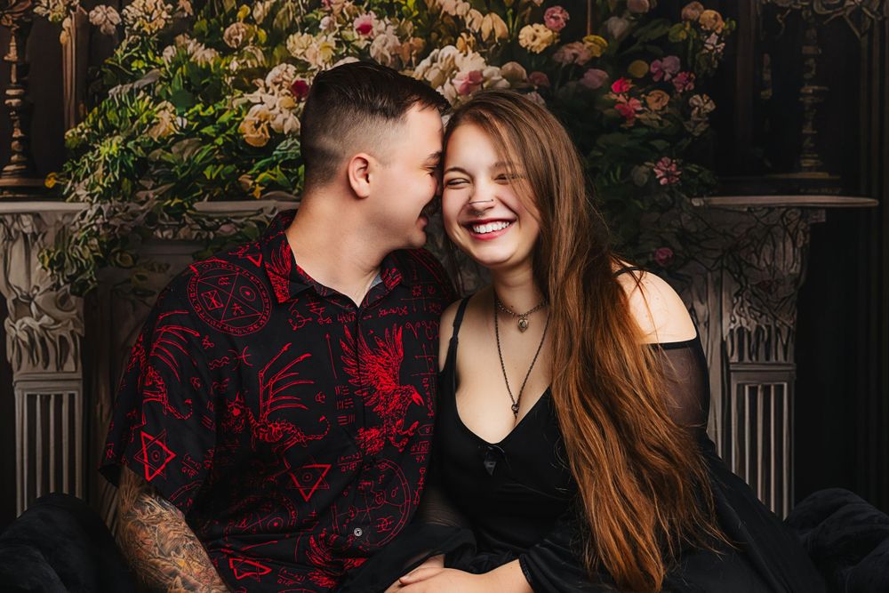 Romantic portrait of a couple sharing an intimate moment against a floral backdrop with pink roses.