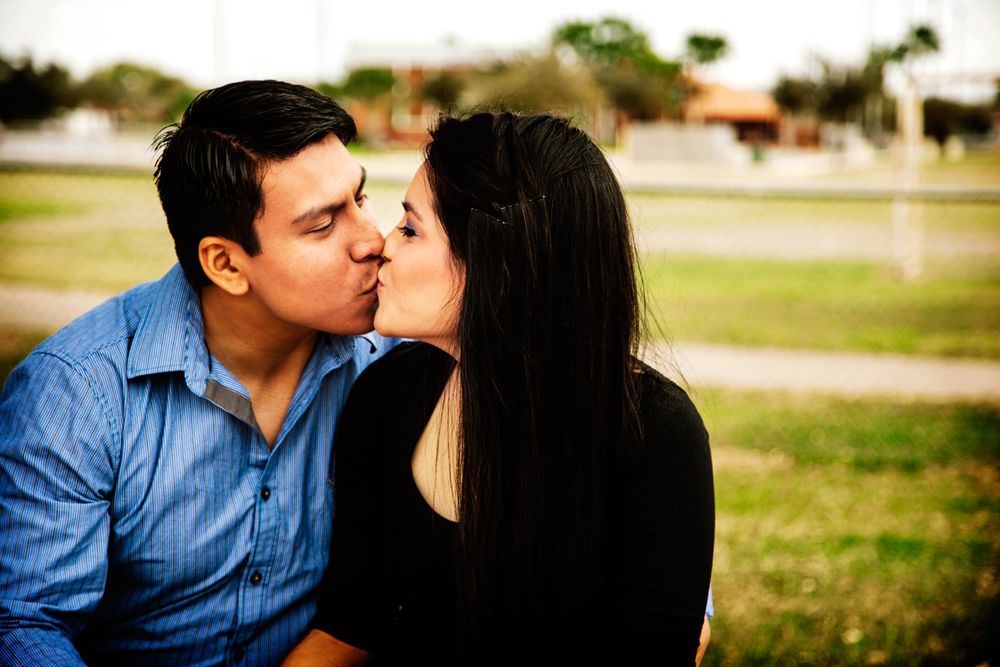Couple sharing an intimate kiss outdoors on a sunny day.