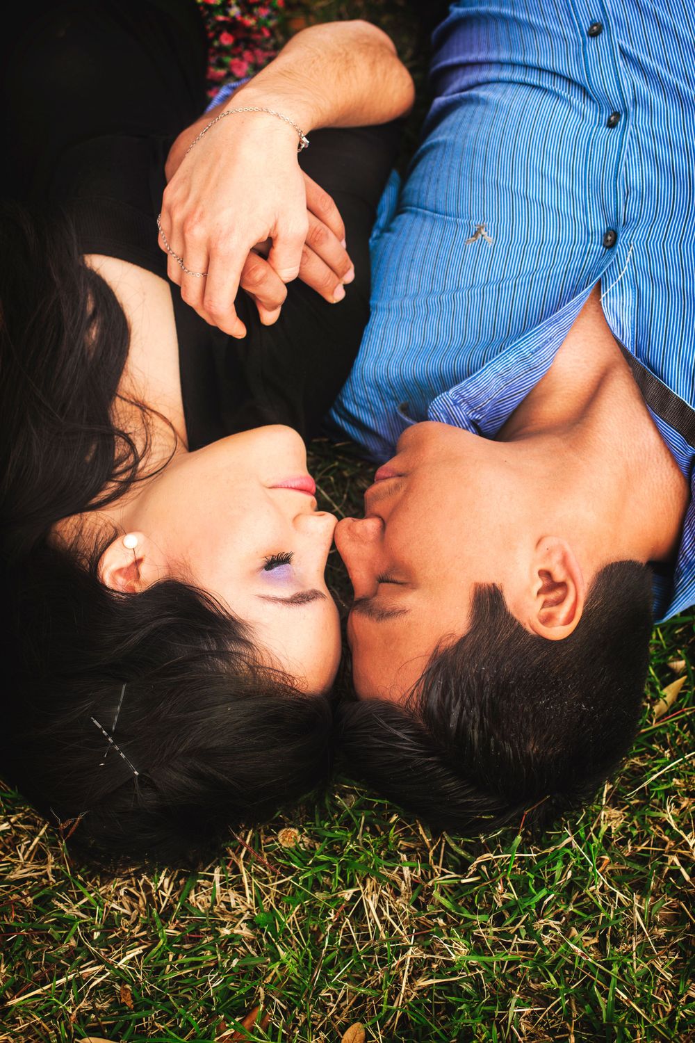 Couple lying on grass in romantic pose during outdoor photo session.