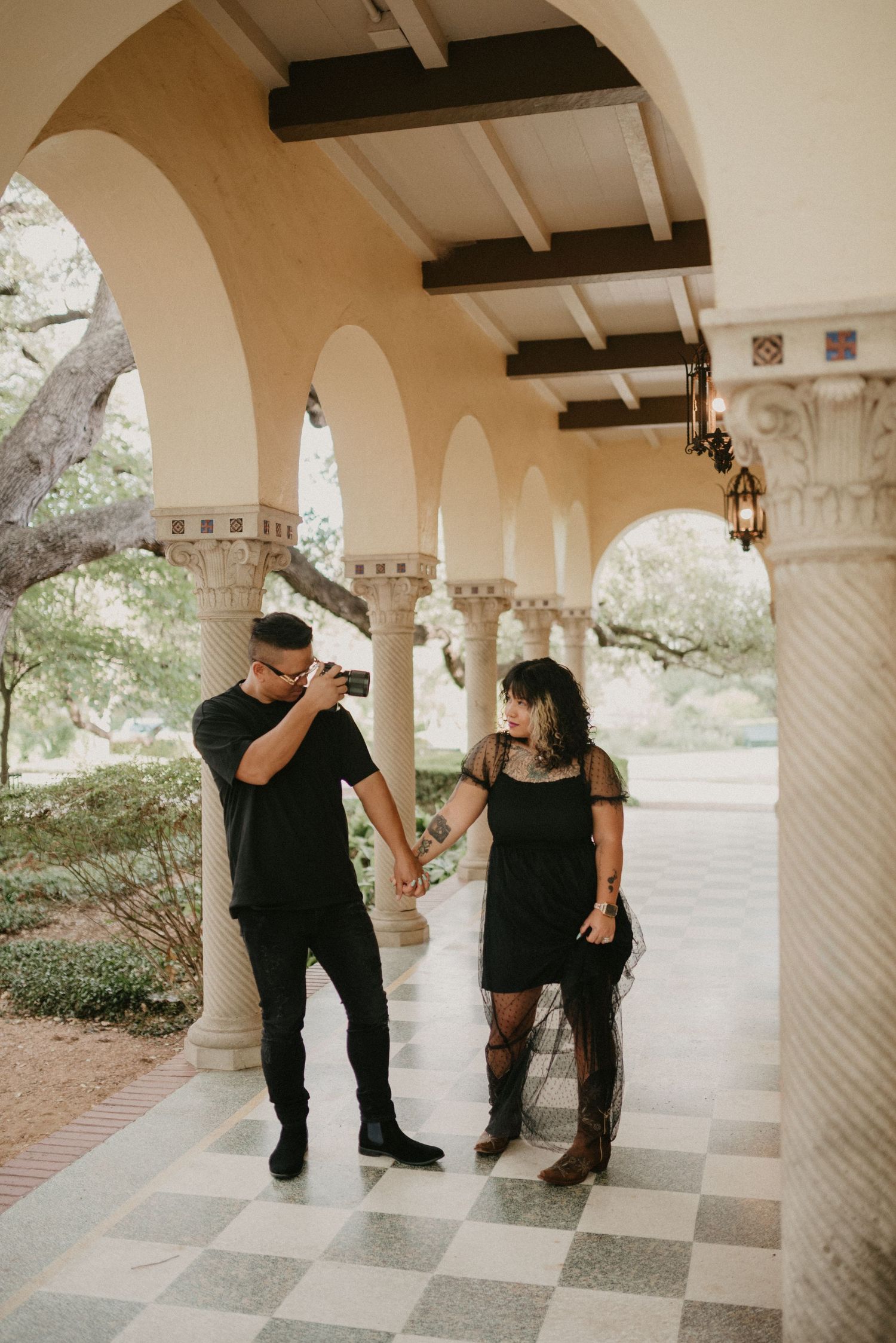 Two photographers working with camera equipment under ornate stone arches and columns.