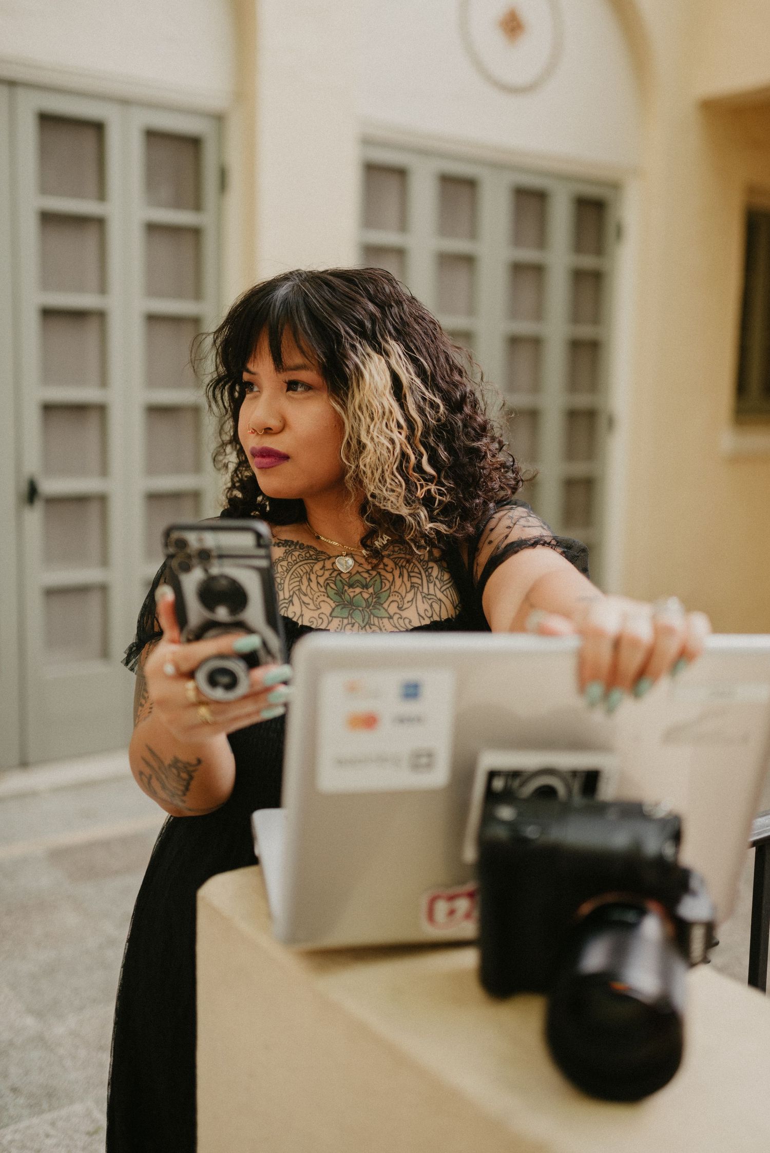 A photographer works with vintage cameras and equipment on a patio with cream-colored walls.
