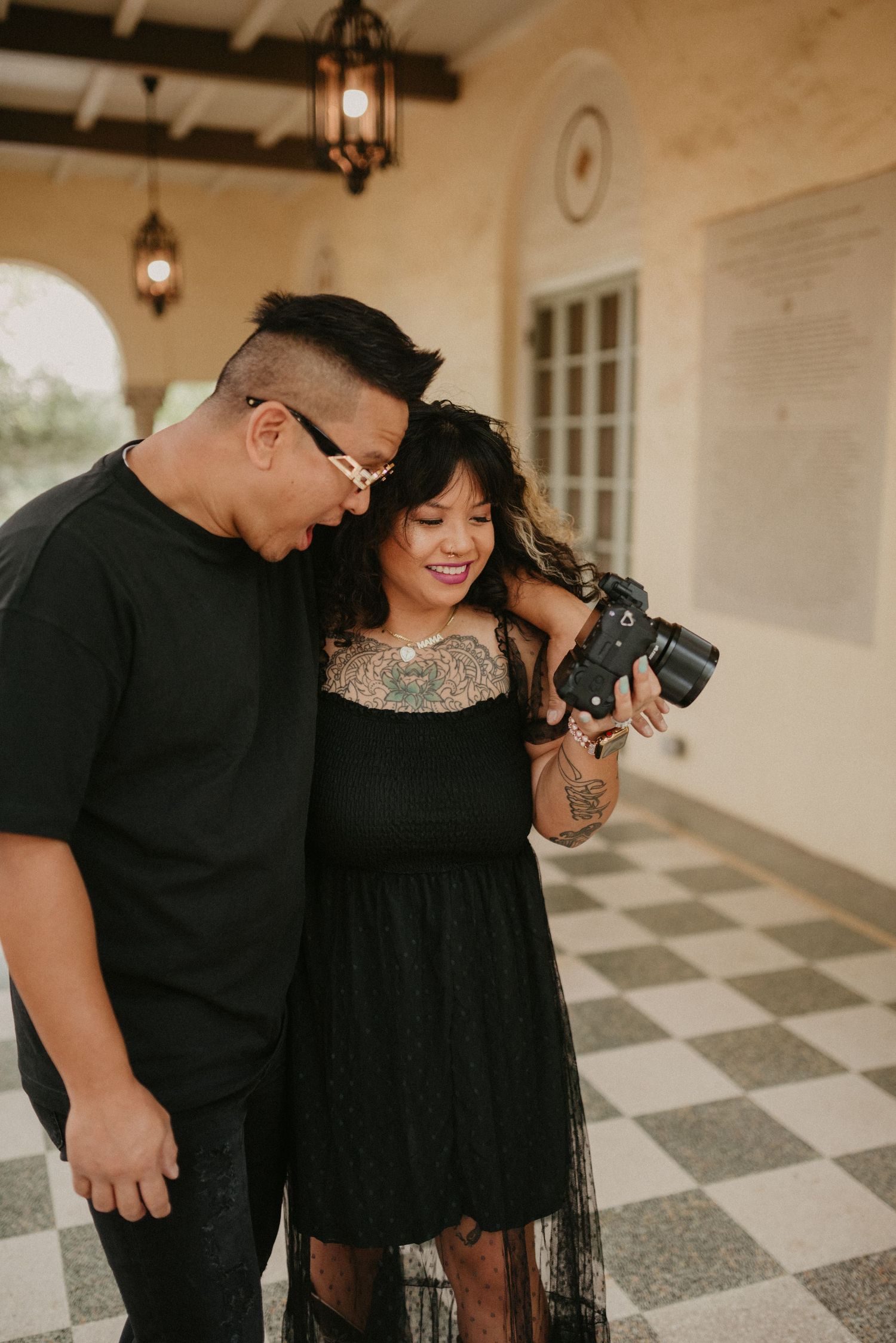 Two photographers review camera shots together in a Mediterranean-style colonnade.