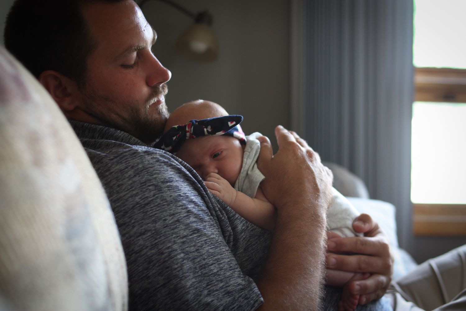 Dad holding newborn daughter in their home in Sioux City, IA.