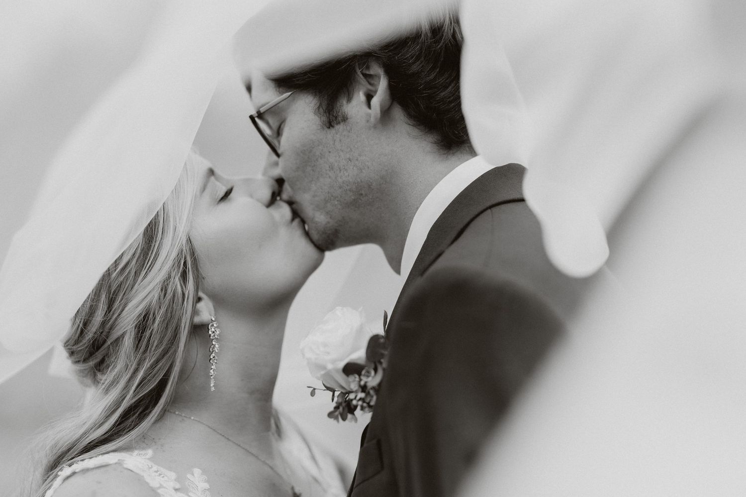 An intimate black and white close-up of a couple sharing a tender moment under a veil.
