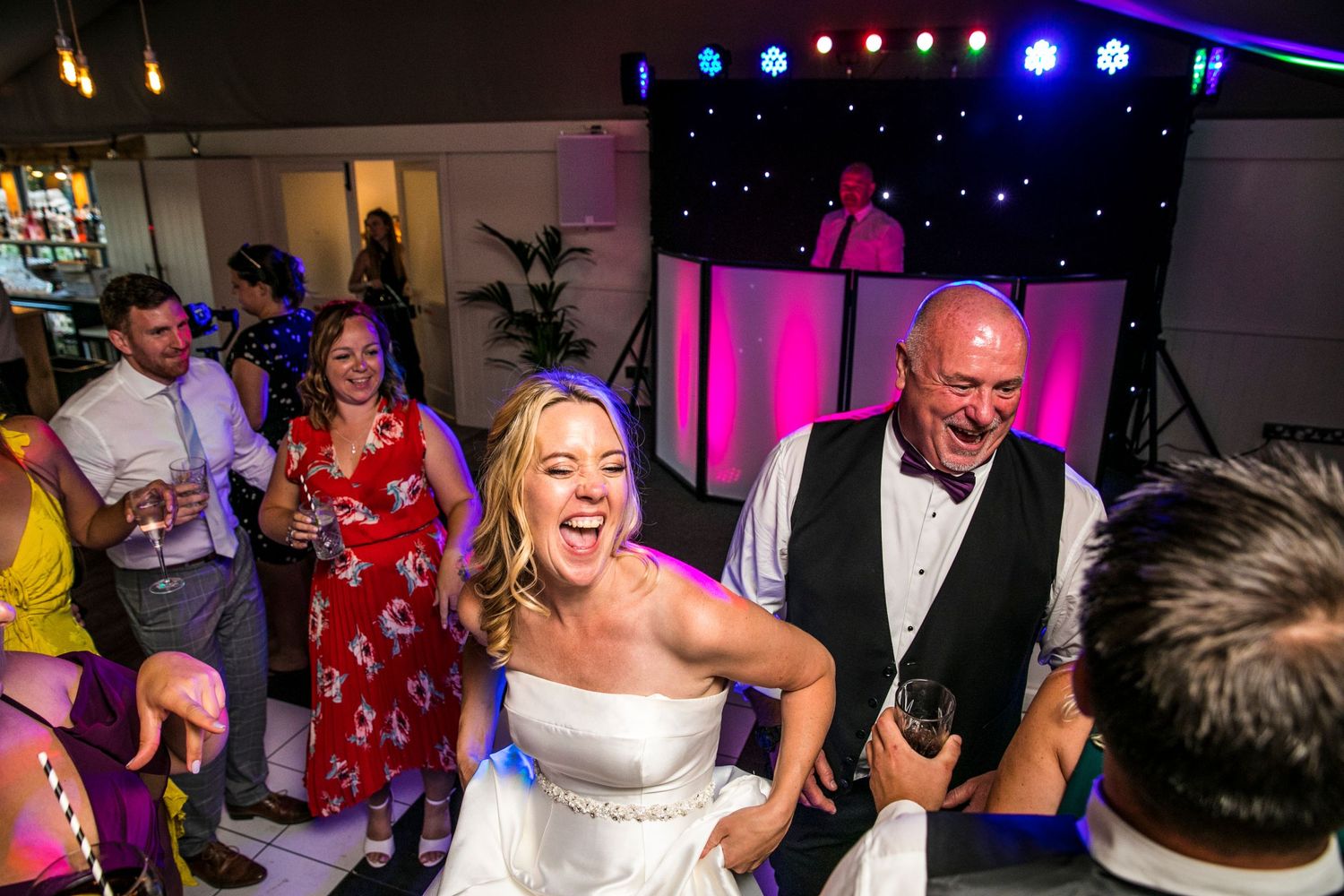 Dance floor celebration with colorful lighting at evening wedding reception.