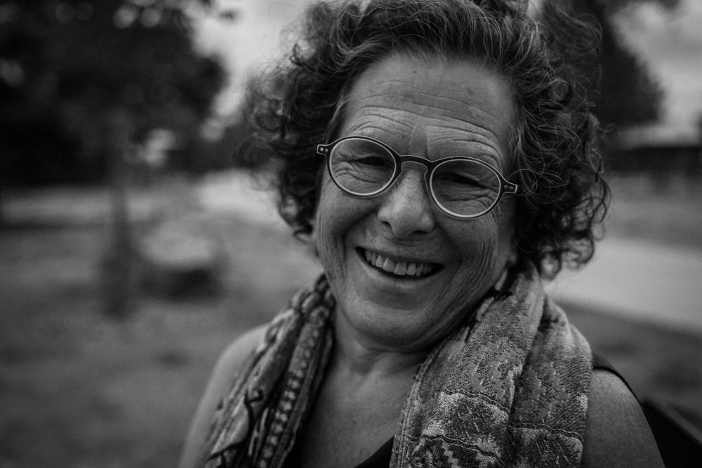 A joyful portrait in black and white showing curly hair and glasses.