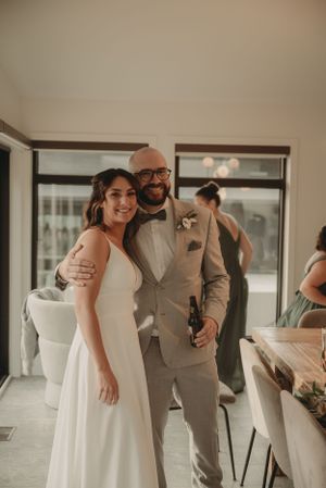 A couple in wedding attire poses together in an elegant indoor setting.