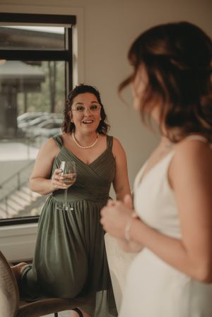 Two women in formal dresses share a conversation while holding wine glasses.
