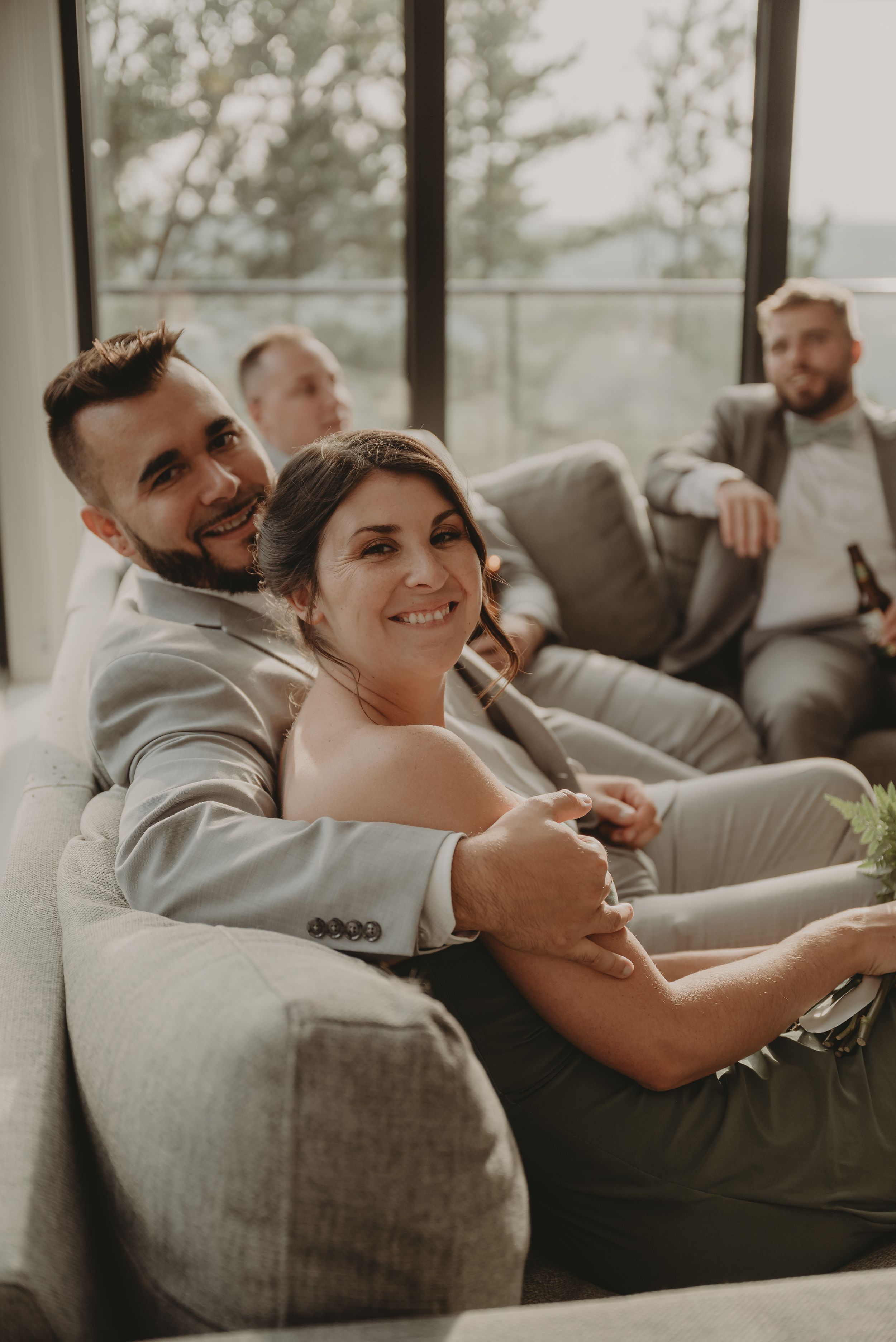 A couple shares an intimate moment on a couch during their wedding celebration.