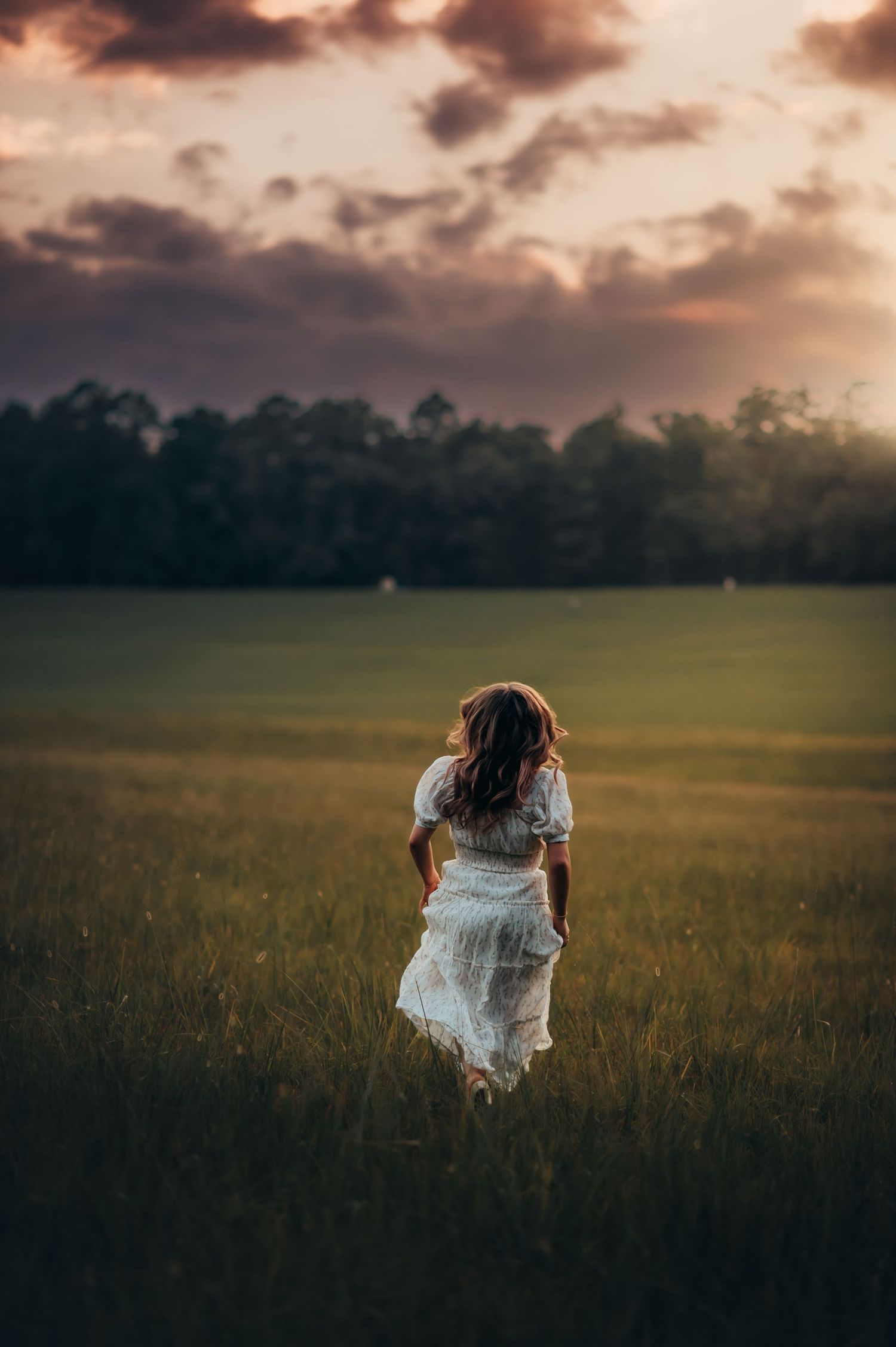 a woman in a white dress running away through Chickamauga Battlefield at sunset for senior photos