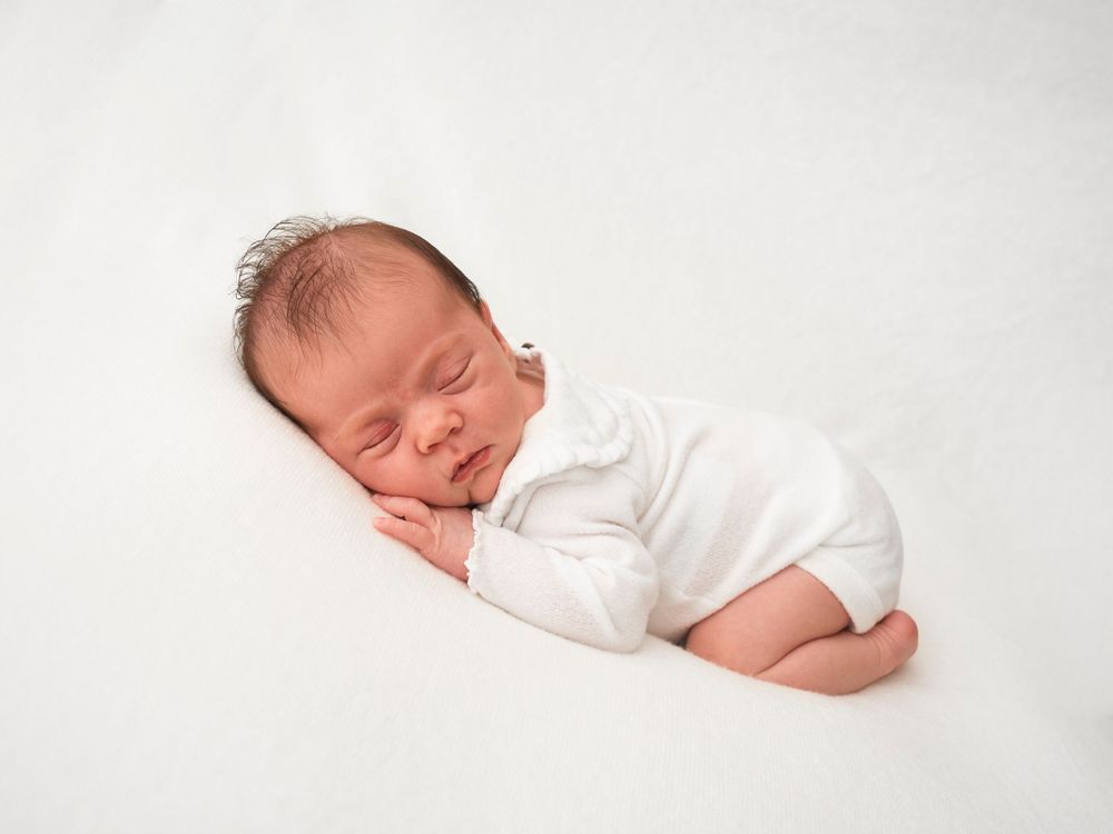 Newborn baby sleeping on white blanket, photoshoot in Didcot by Verity Photography