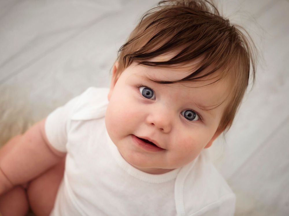photo of sitting baby from above looking up and smiling at camera, photoshoot in Didcot