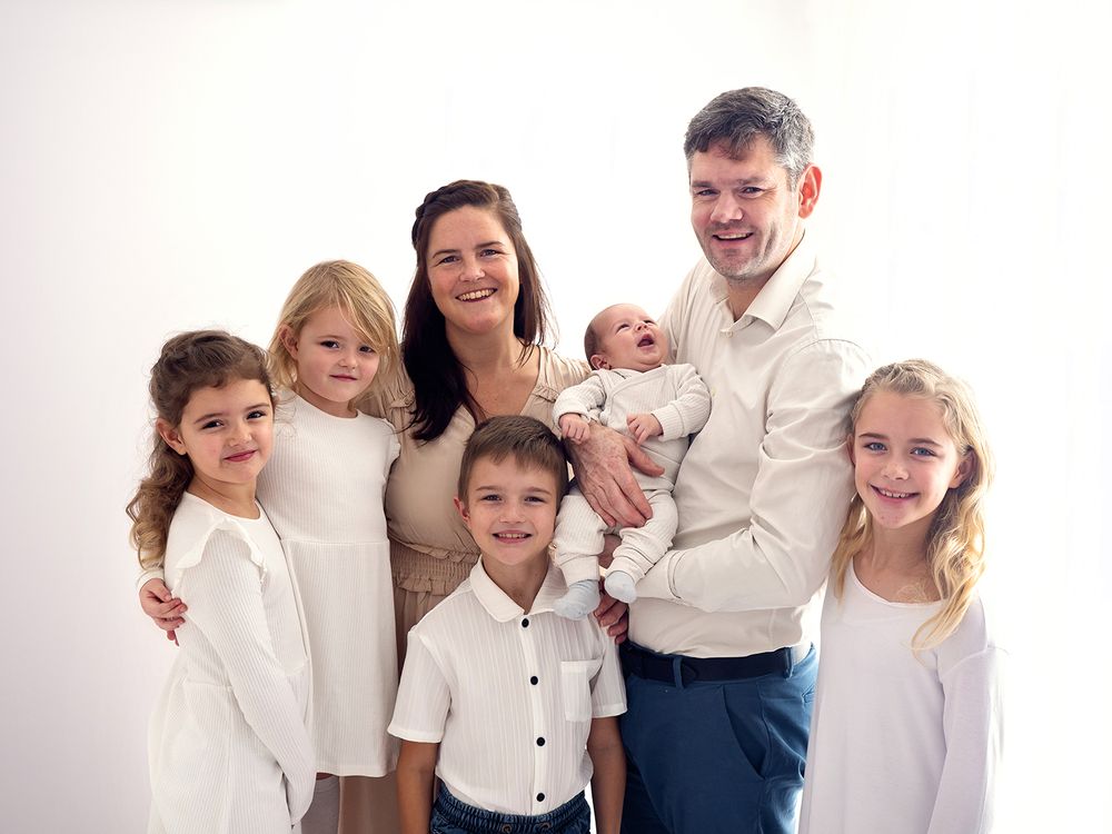 A family wearing white pose with their four children and newborn baby for a portrait with Verity Photography, in Didcot
