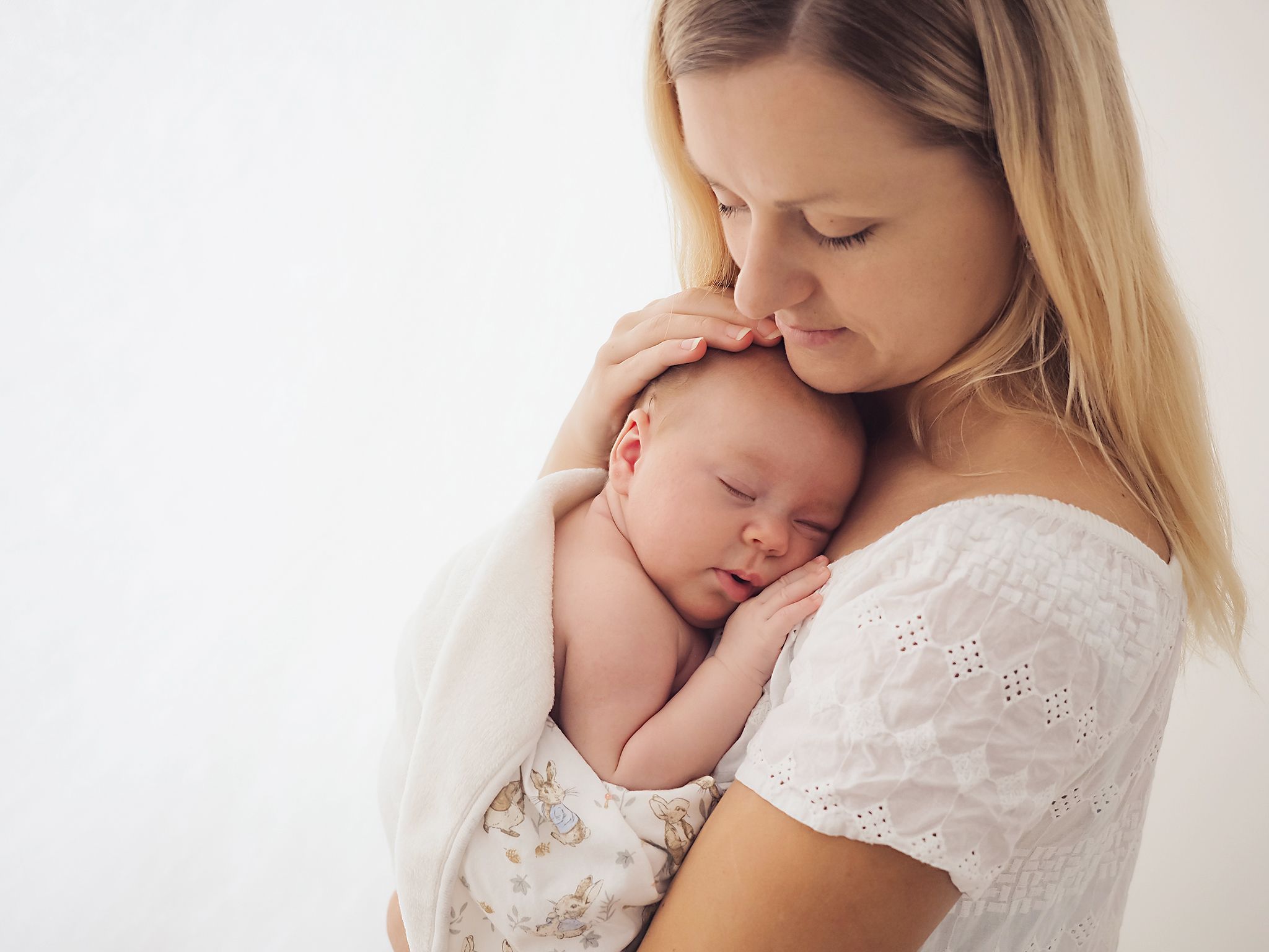 A newborn baby photoshoot of a mother holding the baby wrapped in blanket, by Verity Photography in Didcot