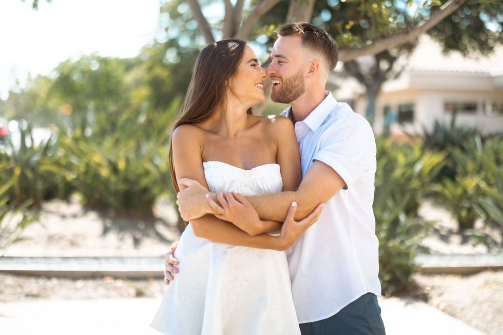 A joyful couple share an intimate moment while embracing in a tropical garden setting.