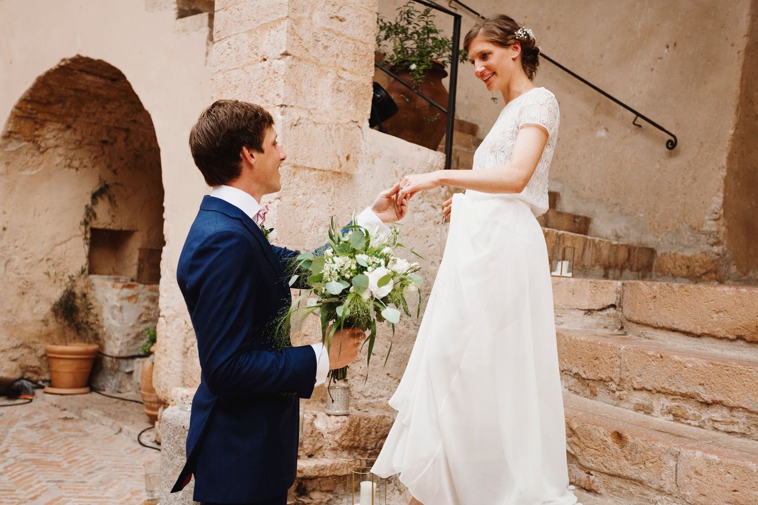 Romantic proposal scene with couple in formal attire at rustic stone courtyard.