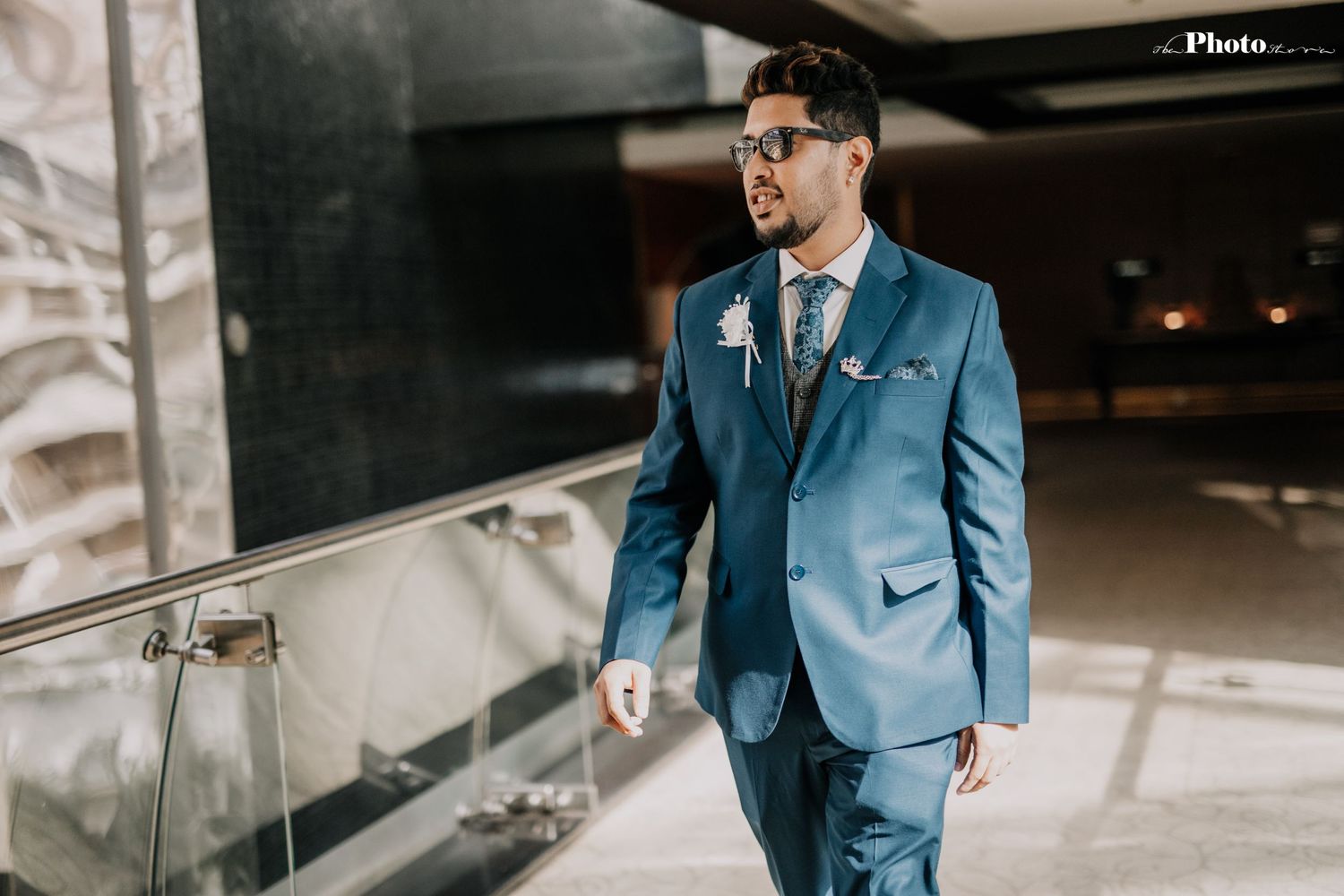 Person in a blue suit walks through a contemporary building with glass railings.