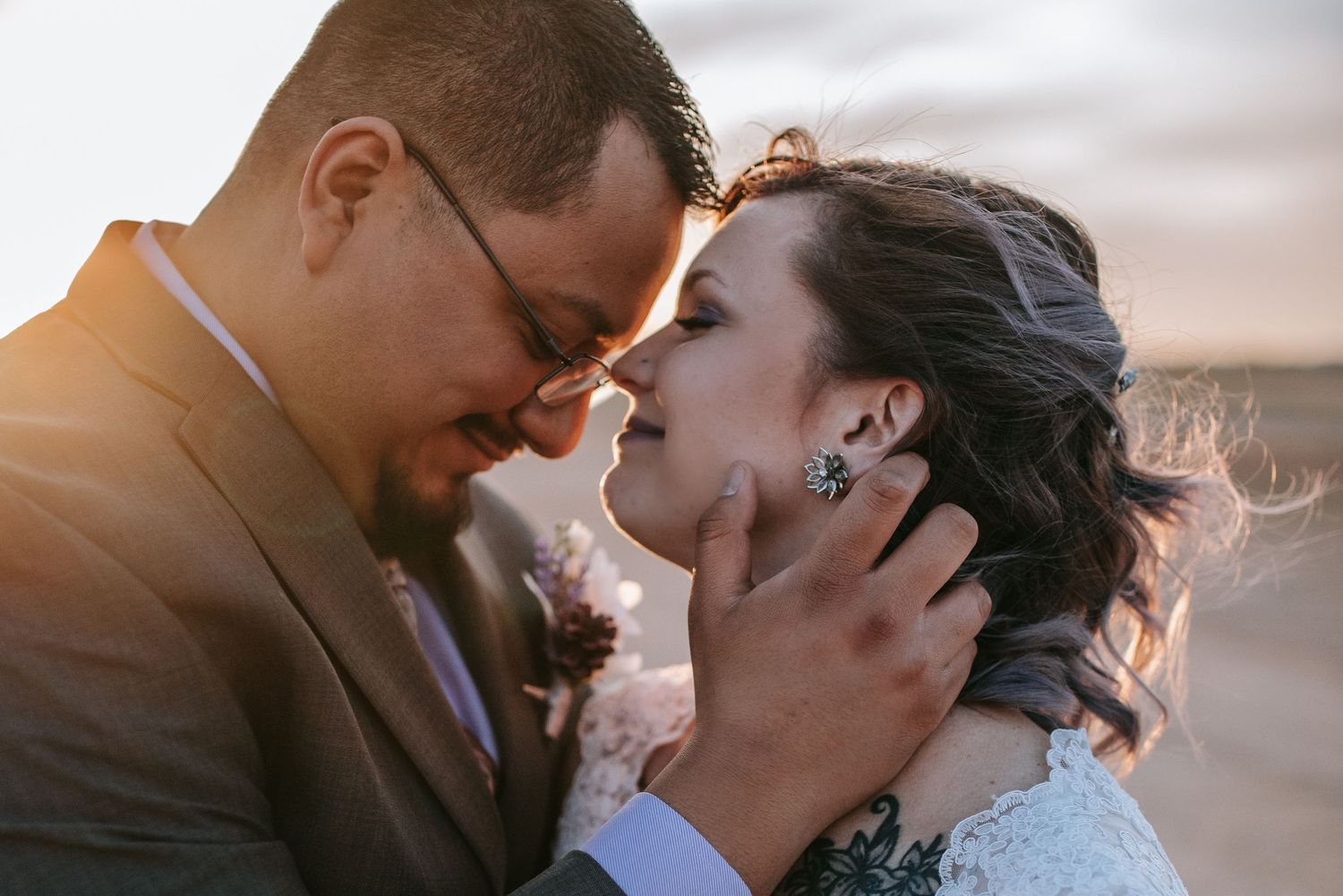 Romantic wedding portrait of a couple sharing an intimate moment at sunset.