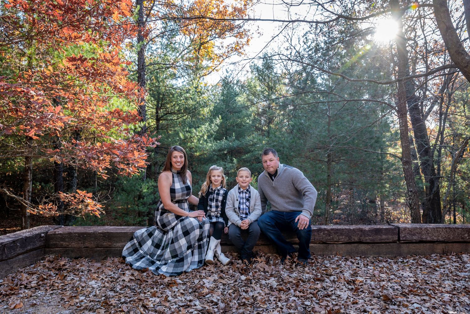 Fall family photo session among colorful autumn leaves and evergreen trees.