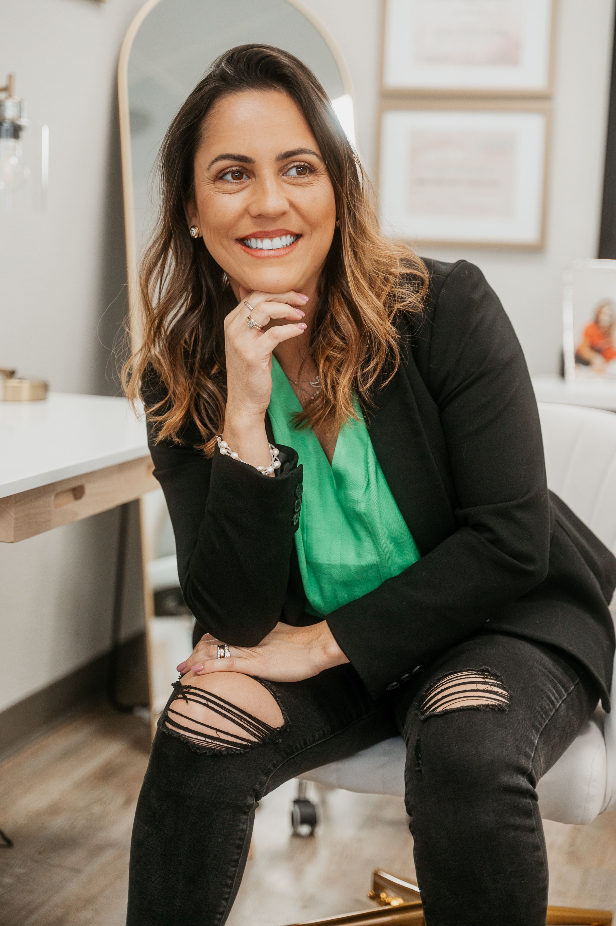 A professional poses in business attire with a bright green top in an office setting.