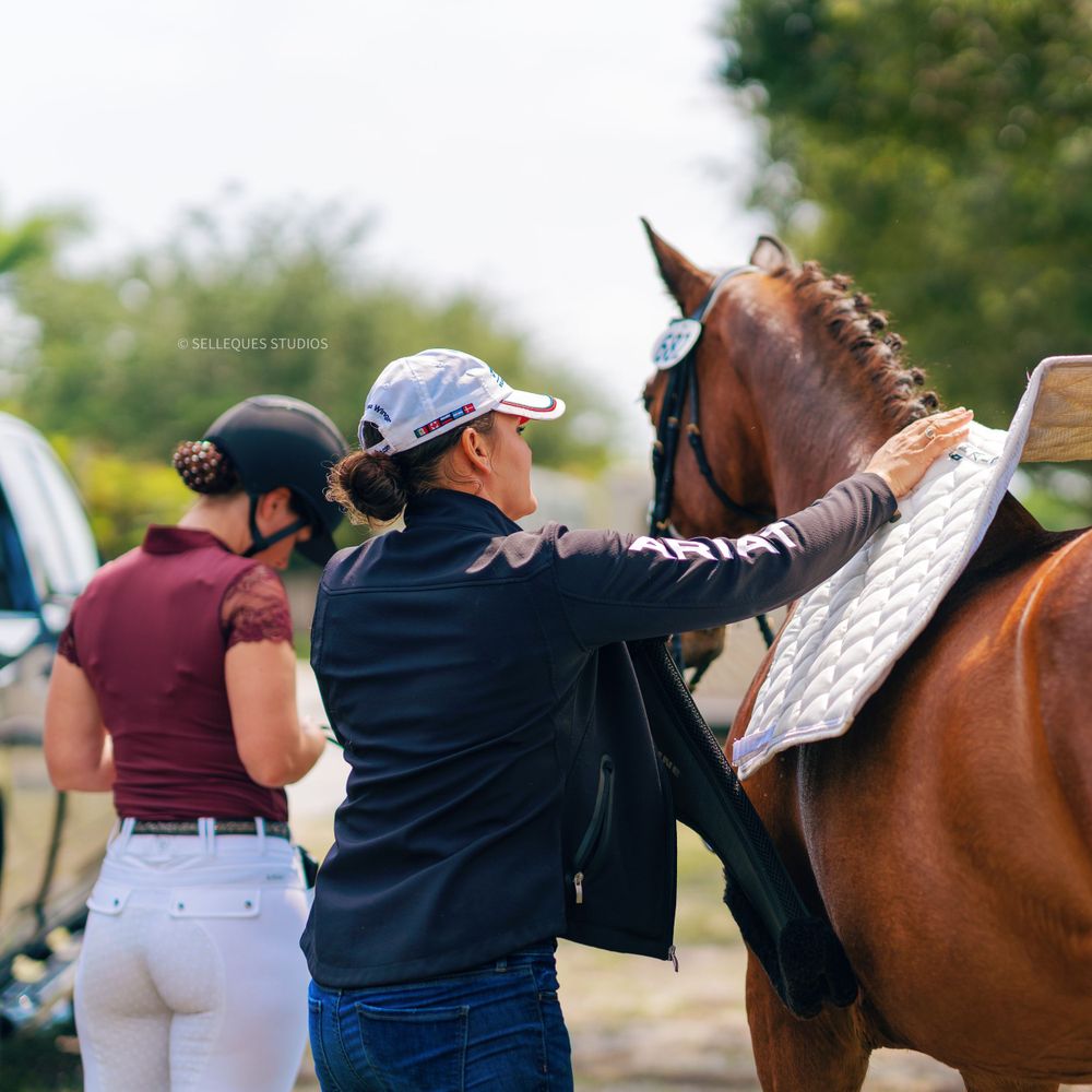 Equestrians preparing a horse for competition at an outdoor event.