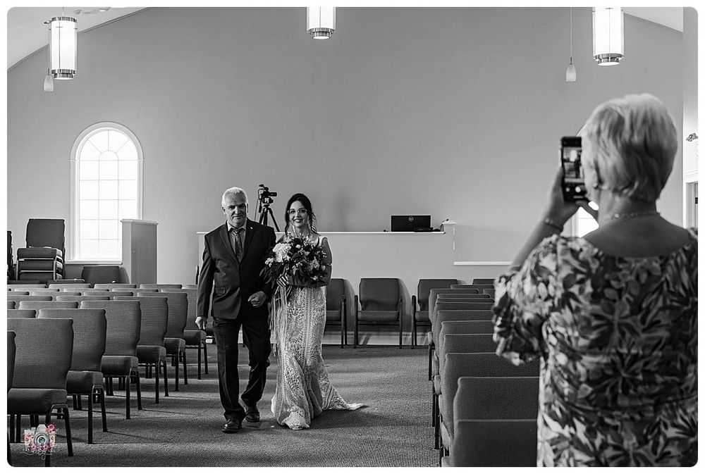 Black and white photo of a procession being captured in a chapel with arched windows.