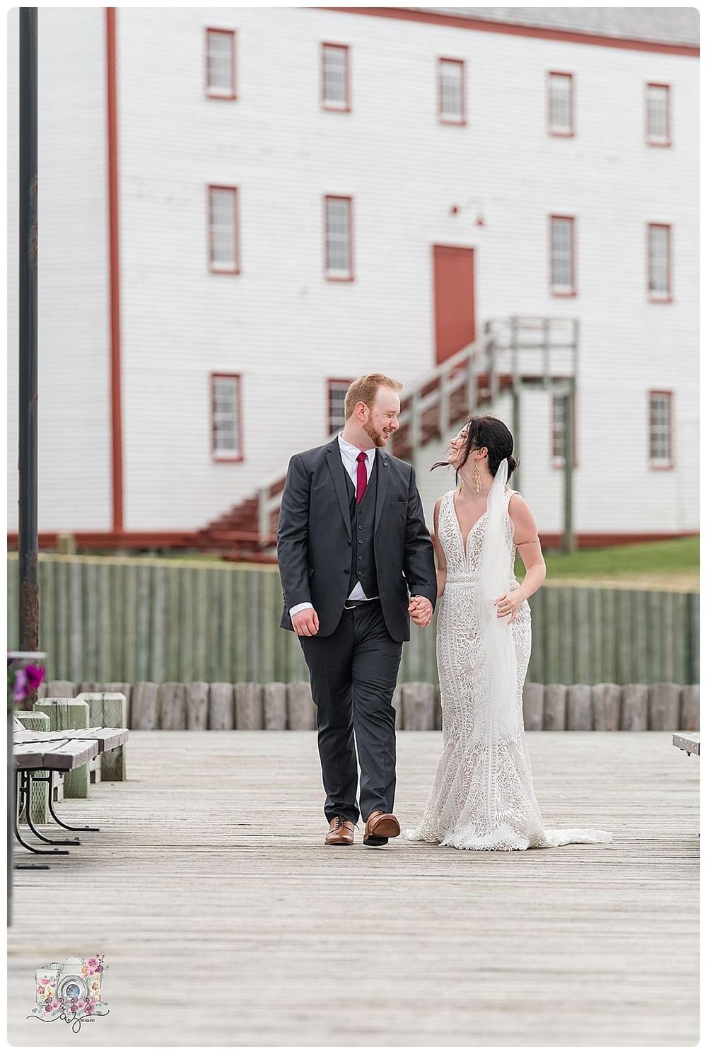 A romantic stroll along a wooden boardwalk with a historic white building in the background.