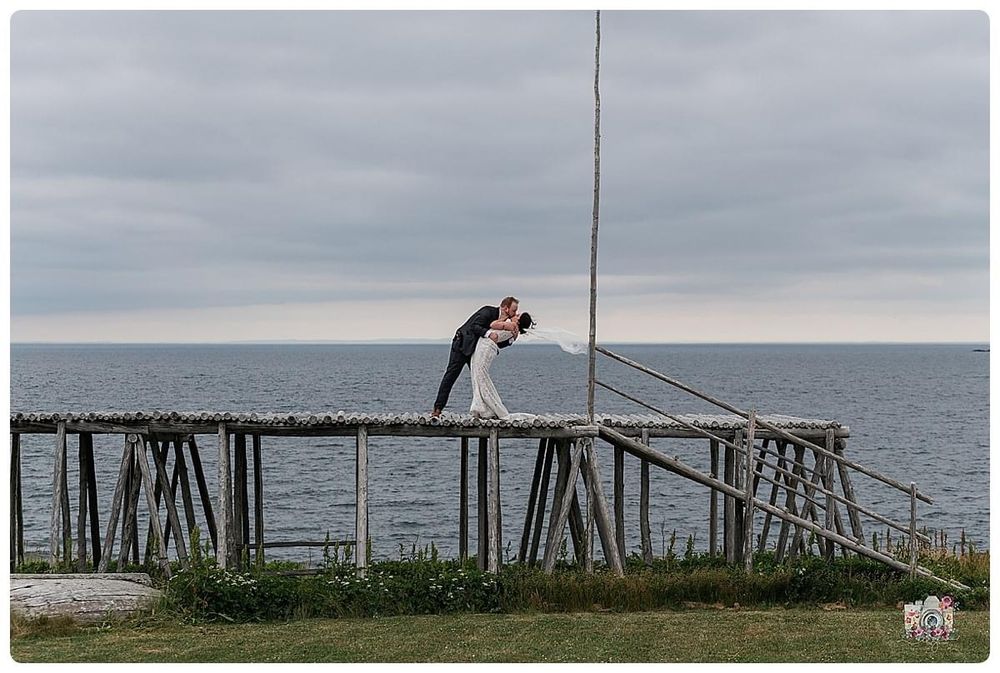 Romantic silhouette pose on an oceanside wooden structure against a cloudy sky.