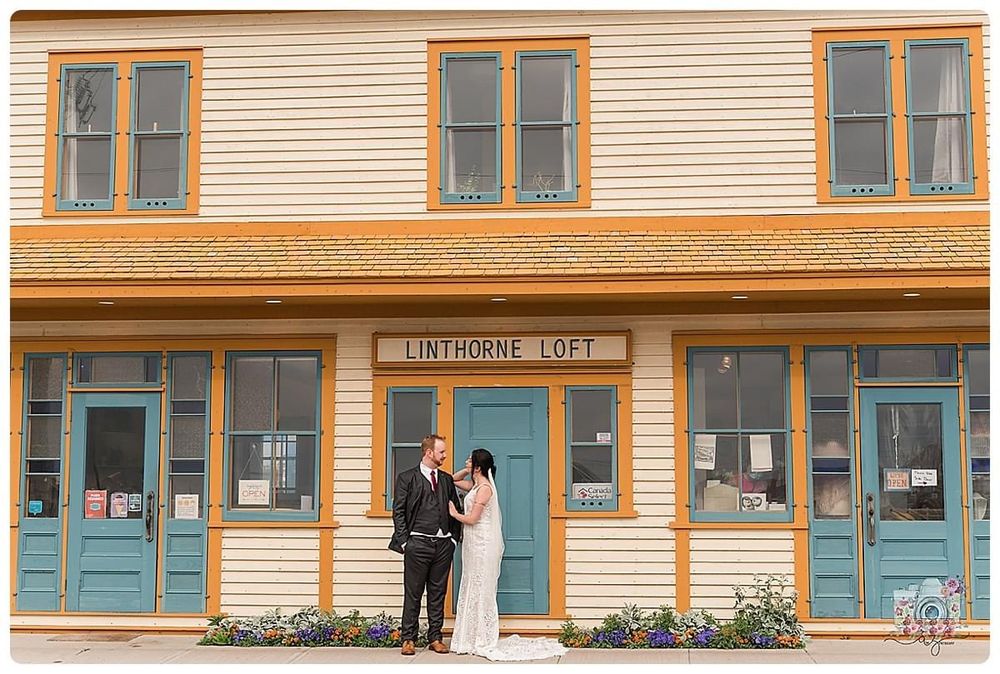 Couple stands in front of historic yellow building with blue doors called Linthorne Loft.