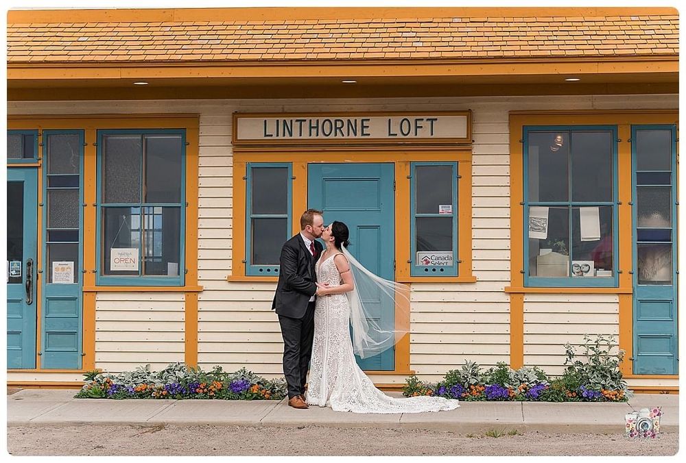 Couple poses with flowing veil in front of historic Linthorne Loft building.