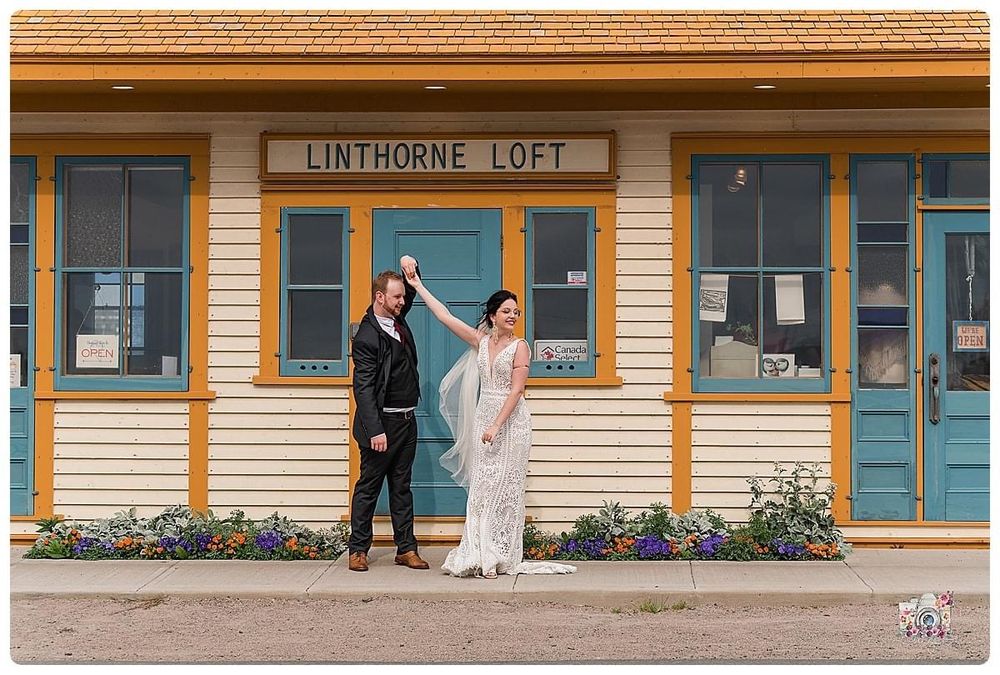 Wedding couple poses casually in front of yellow Linthorne Loft building.