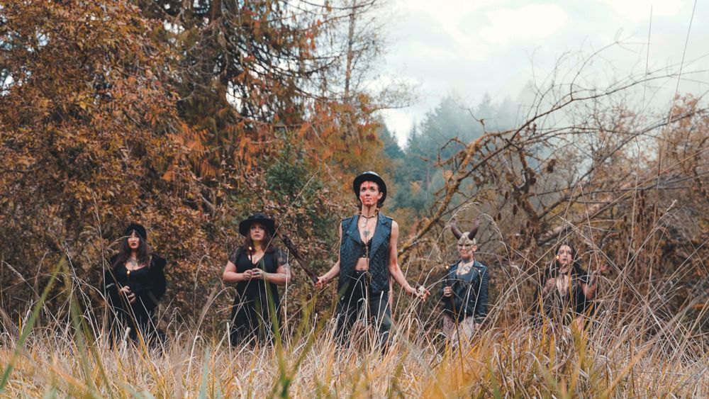 A group poses together in a field during autumn with dried grass and fall foliage.