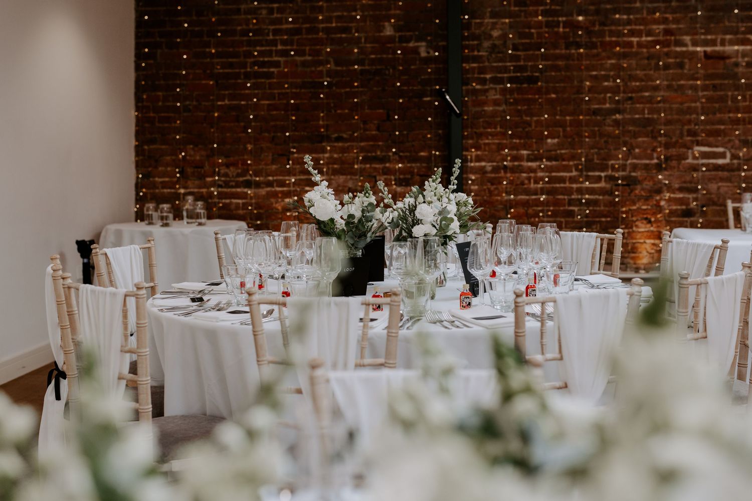 wedding reception room dressed with white linen and white roses.