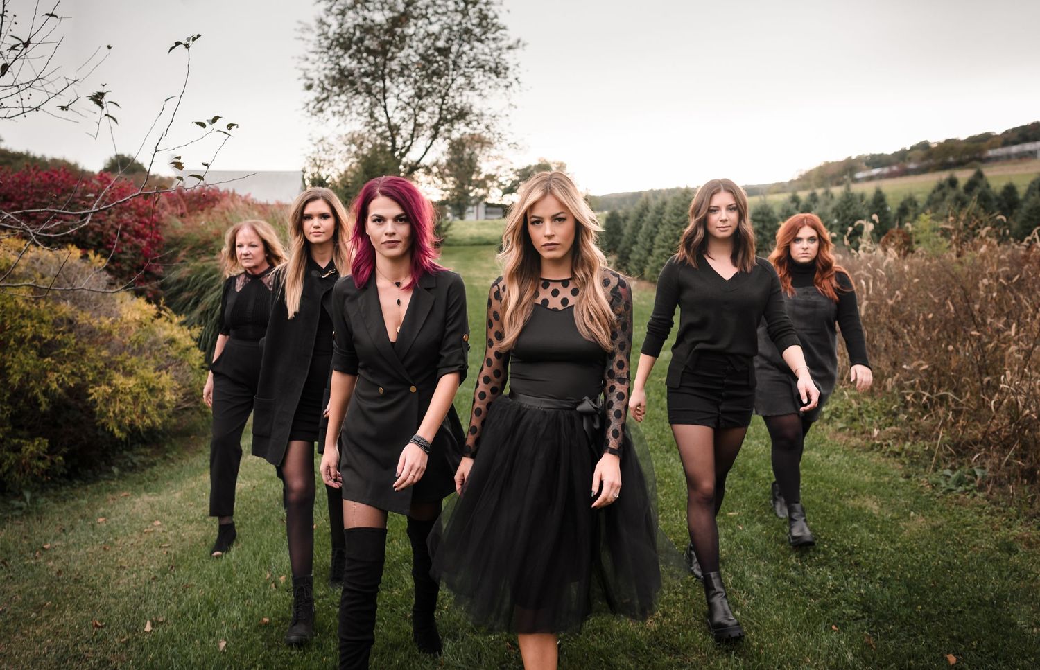 Group photo of people in black outfits posing outdoors in autumn setting.