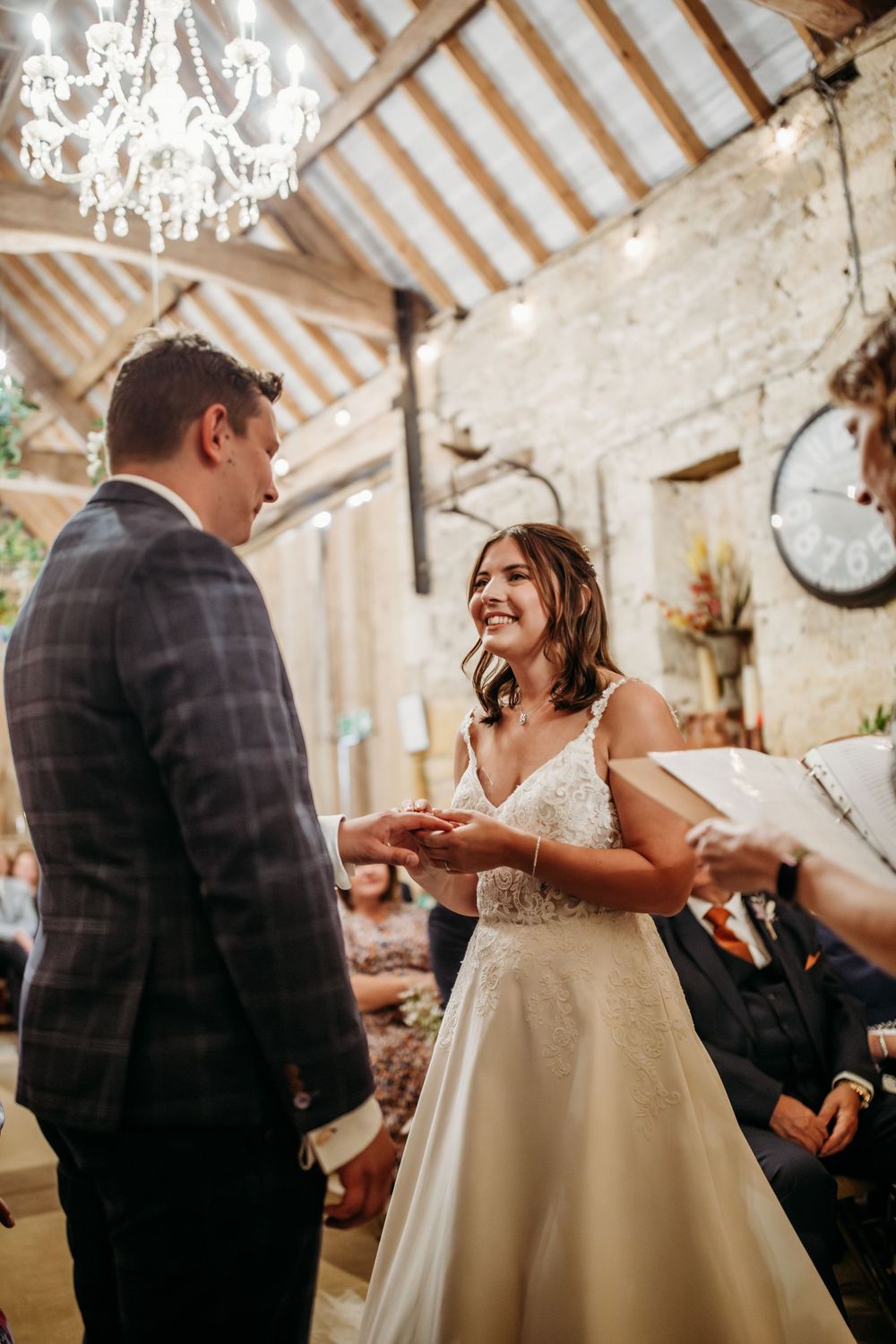 A couple exchanges rings during an intimate wedding ceremony underneath an elegant crystal chandelier.