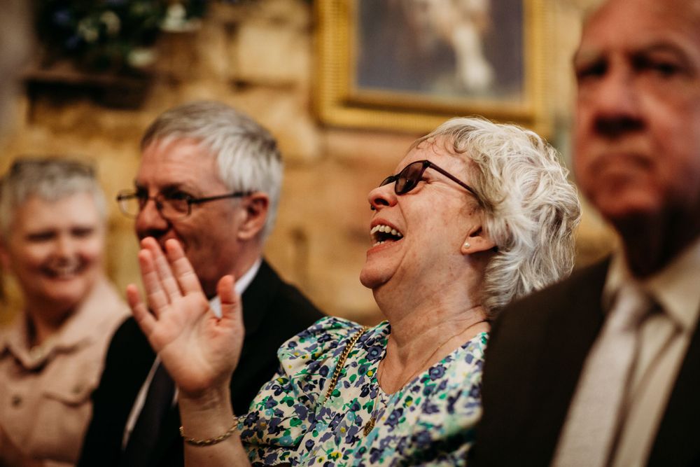 Wedding guests share laughter and emotion during a heartfelt ceremony moment.