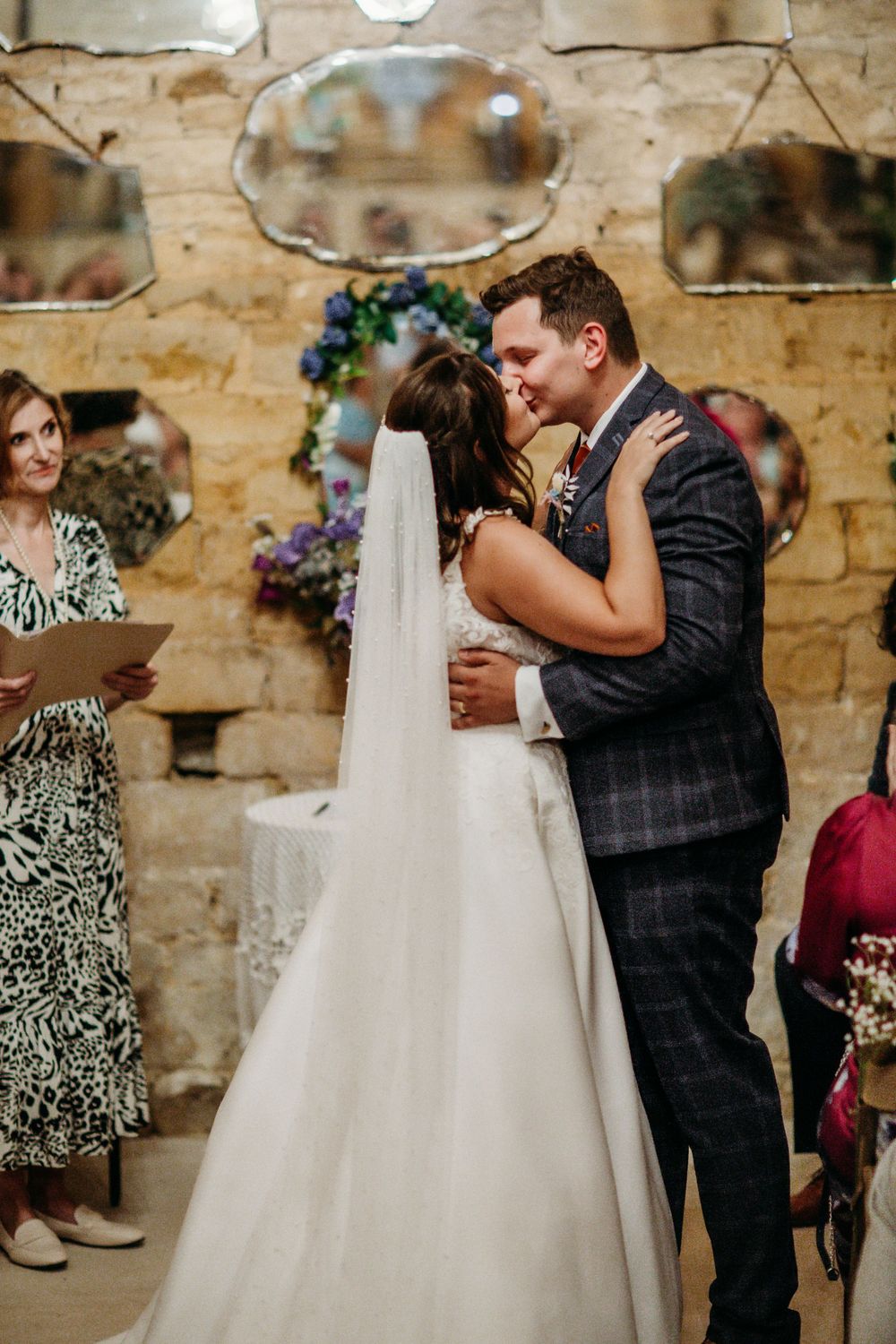 Intimate wedding ceremony moment in a rustic stone venue with decorative mirrors and floral arrangements.